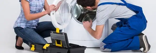 Washer repair technician inspecting a front-load washing machine with tools in Shreveport, LA