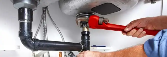 Garbage disposal repair technician tightening the sink drain and disposal connection in Shreveport, LA
