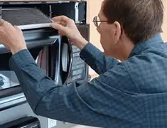 Appliance repair technician replacing a microwave vent filter in Shreveport, LA