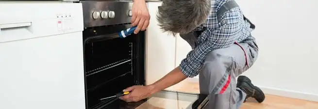 Oven repair technician inspecting and servicing an electric oven in Shreveport, LA