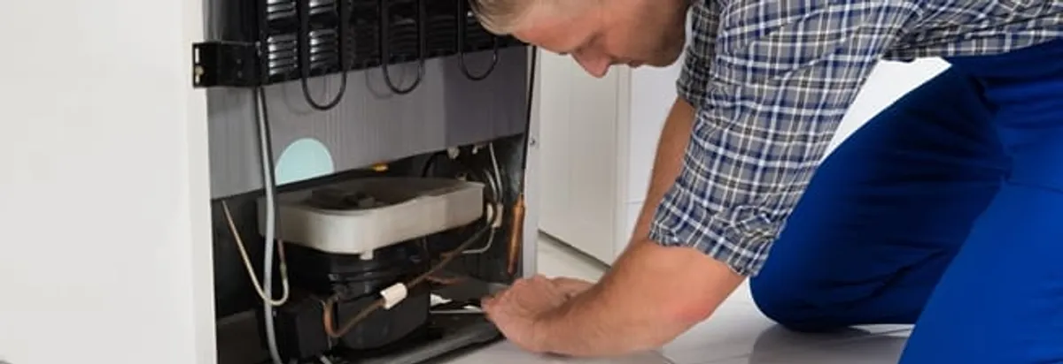 Refrigerator repair technician servicing the compressor and condenser area in Shreveport, LA