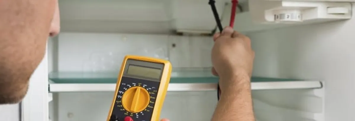 Refrigerator repair technician testing electrical components with a multimeter in Shreveport, LA