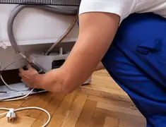 Appliance repair technician fixing refrigerator water line and connections in Shreveport, LA
