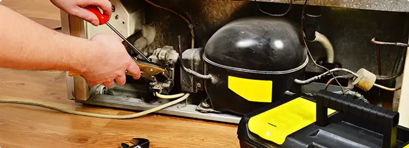 Refrigerator repair technician fixing the compressor and wiring in Shreveport, LA