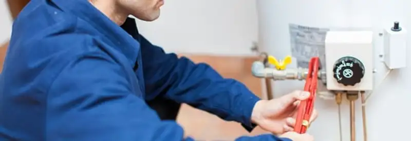 Water heater repair technician adjusting the temperature control and gas valve in Shreveport, LA